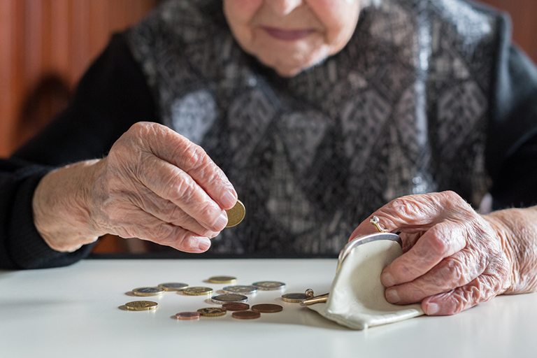 Ältere Frau mit Münzen und Geldbörse